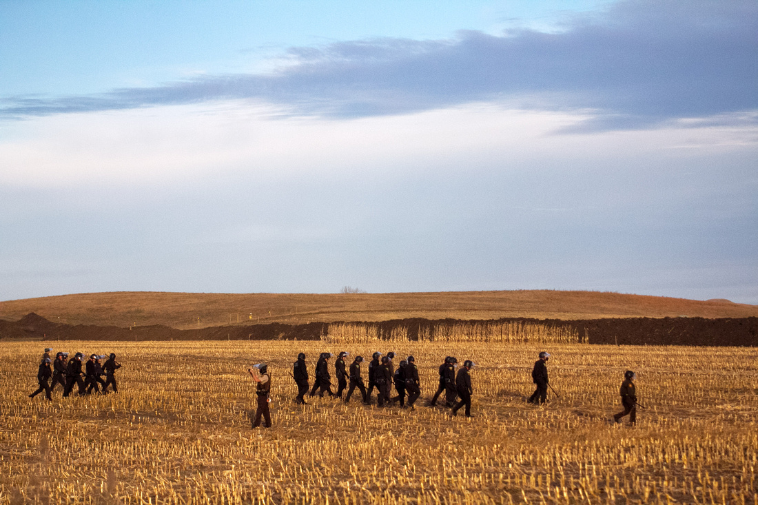 Police at the DAPL construction site move to defensive positions closer to the construction equipment being used to dig the pipeline as marchers move in.