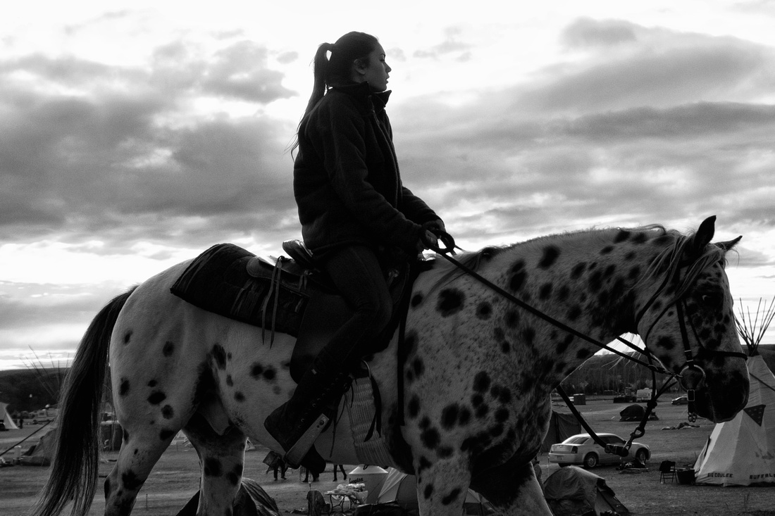 A Native youth rides a horse through the campsite just after sunrise at the DAPL Resistance camp in Cannon Ball, ND. Horses are a common sight around the camp and used primary for transportation.