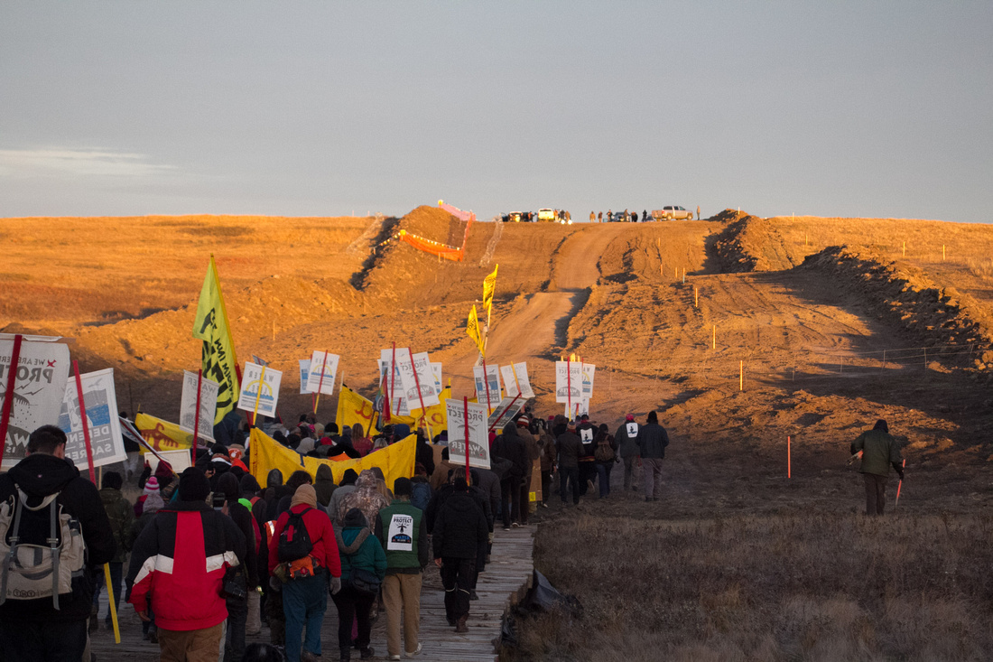 Native Americans and other DAPL Resistance members gather at sunrise for a 5 mile march to the DAPL construction site. Police and private security can be seen on the hill directly in the path of the D