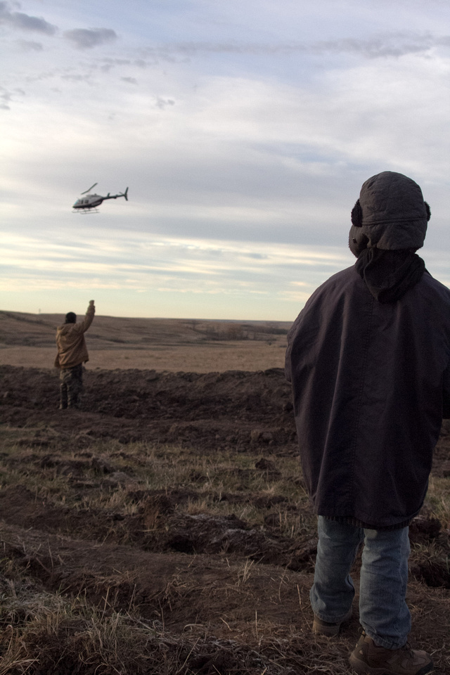 A Native American child watches as a law enforcement helicopter follows Native American Water Protectors as they walk along the path towards the #DAPL construction site.